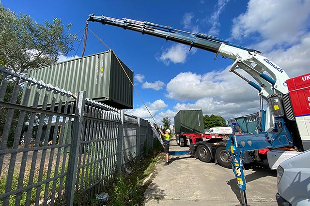 Container being delivered over a fence
