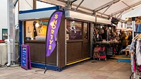 Container market stall with open roller shutters, windows, serving area, and wooden panelling