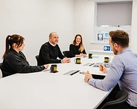 Board room meeting with four people sitting around a table